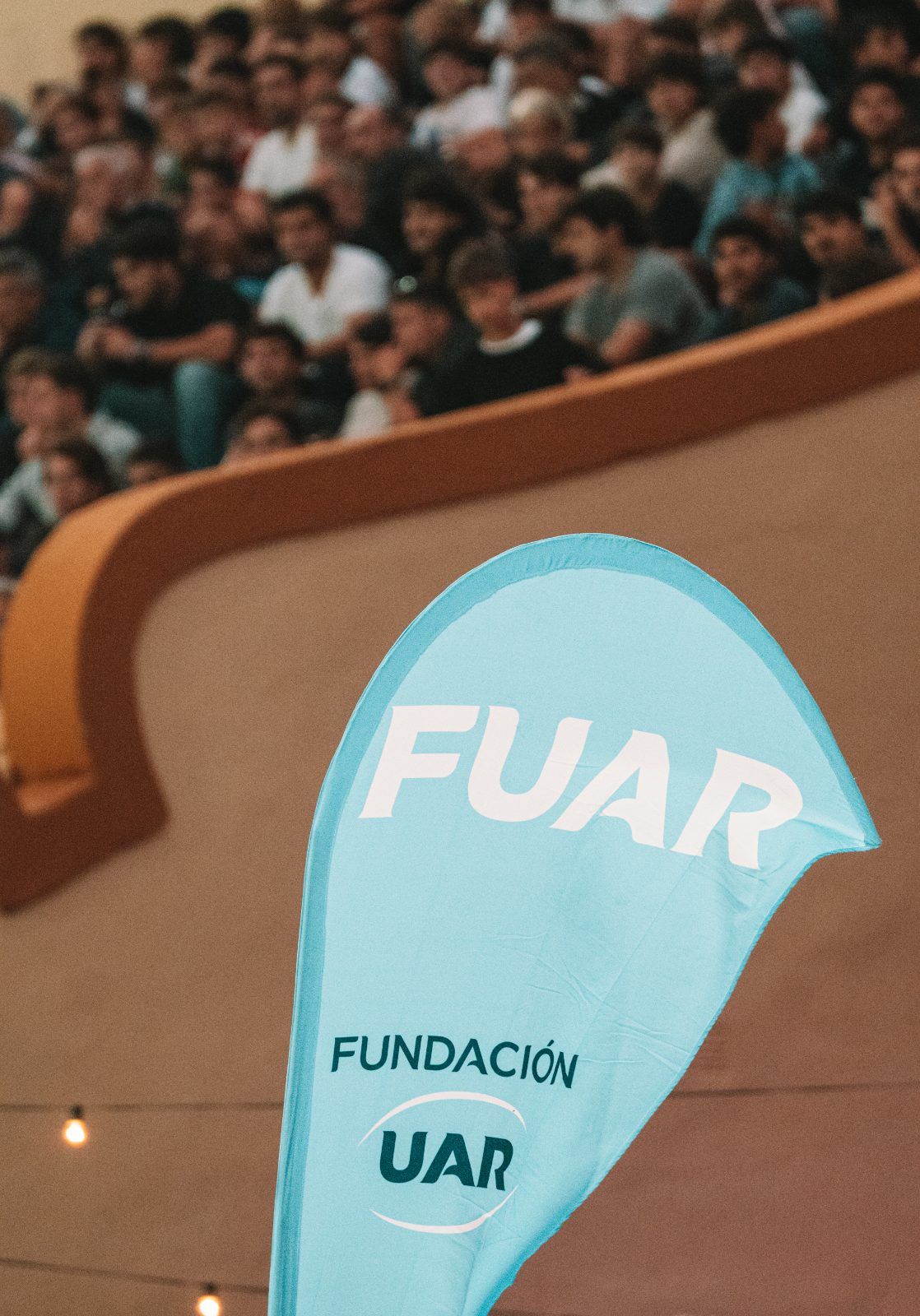 Bandera celeste de Fundación UAR frente a una tribuna llena